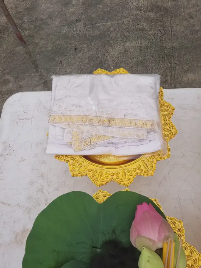 “Gifts: Ceremonial robe, with lotus flower bud (and lotus holding the cut hair)”
